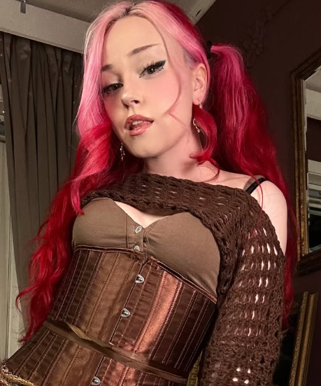 Alice Starr tar et bilde iført et sexy brunt antrekk med rosa hestehaler.