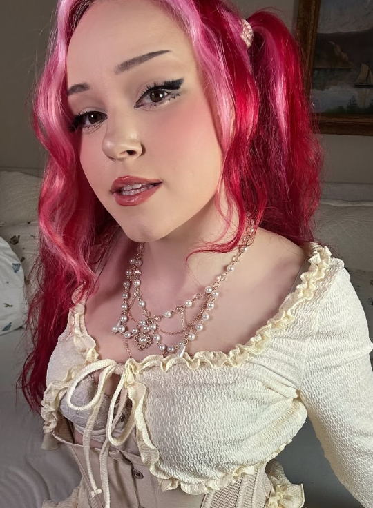 Alice Starr tar en selfie på rommet sitt kledd i en hvit topp og med et perlekjede.