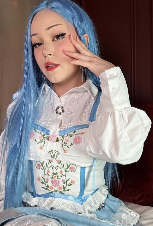 Alice Starr tar et bilde i en blå og hvit kjole og med en blå lang parykk.