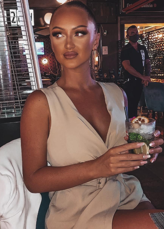 @christinalegreid tok et bilde på en restaurant og kledde seg i et beige antrekk mens hun holdt en cocktail i hånden.