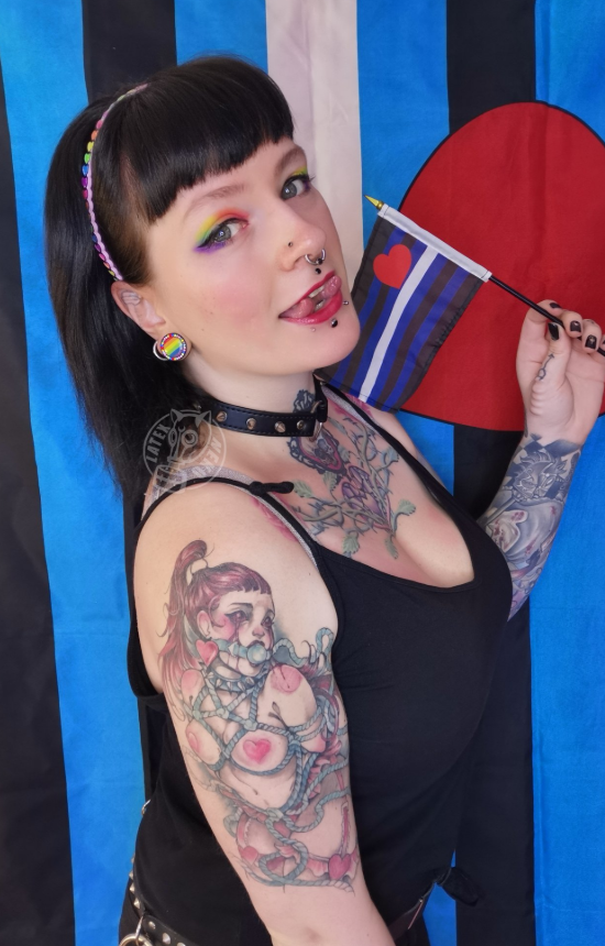 @latex_neko kledd i en sexy svart topp og jeans mens hun holdt et flagg.