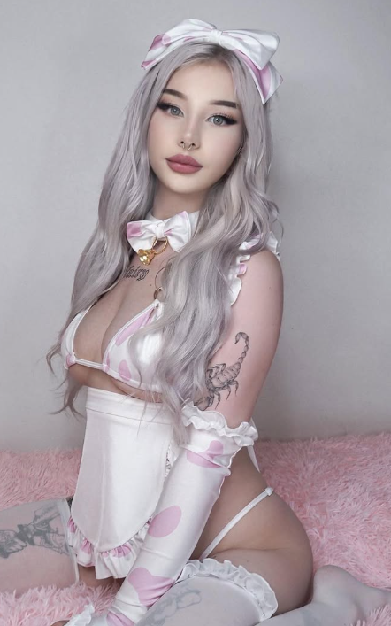 @Pastelhaze sitter på en rosa seng og er kledd i et sexy rosa og hvitt hushjelpantrekk.