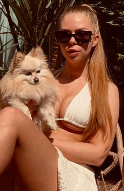 @thebellebunny tar et bilde kledd i en sexy hvit BH og et hvitt skjørt mens hun holder hunden sin.