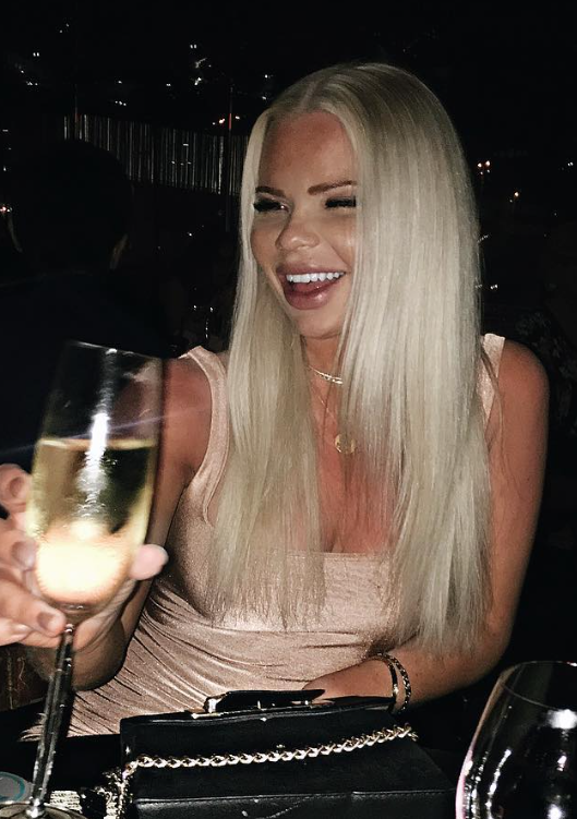 @julianyland på en restaurant, tar en drink og har på seg en sexy kjole.