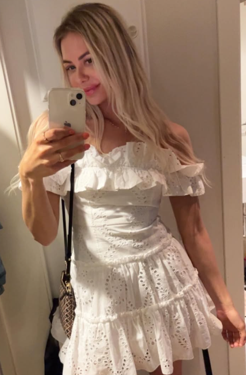 Nora North tar et bilde og er kledd i en sexy, hvit kort kjole.