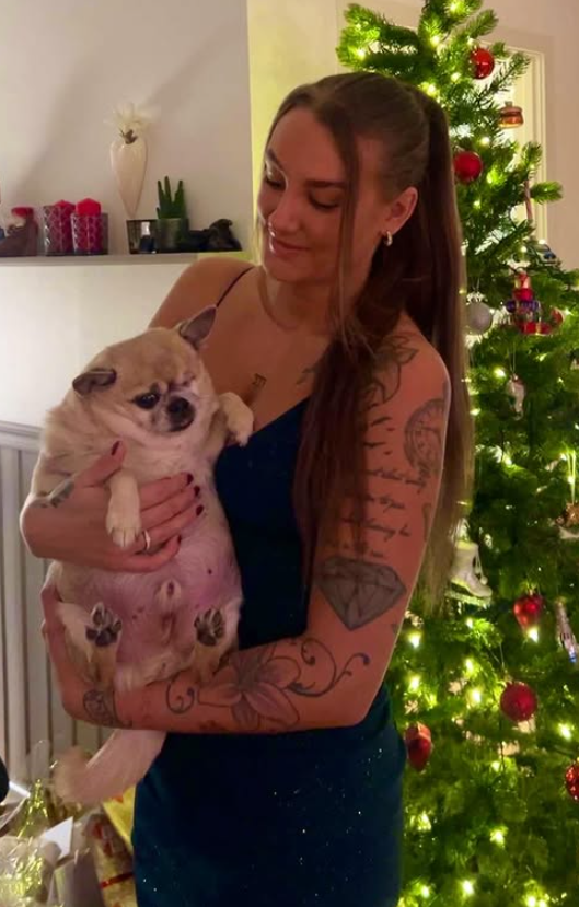 Julie Linnea Hovelsen tar et bilde med hunden sin foran et juletre kledd i et sexy svart antrekk.