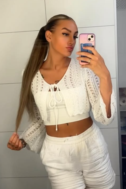 Julie Linnea Hovelsen tar et bilde mens hun er kledd i en sexy hvit crop top og hvite shorts.