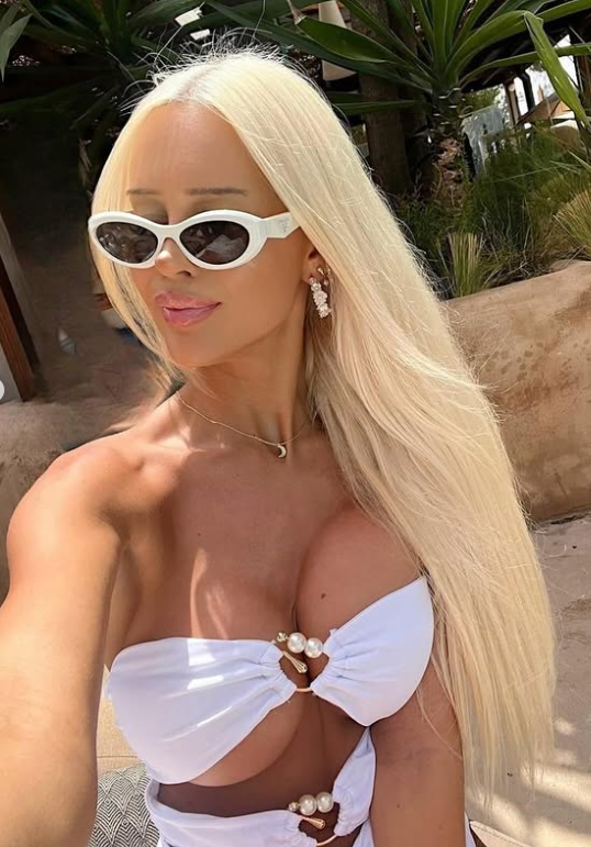 Julie Olivia tar et bilde i et sexy hvitt antrekk og solbriller med hvit innfatning.