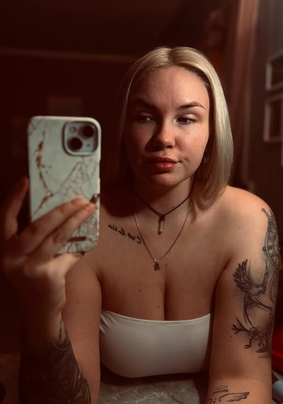 Anja Erika tar et bilde med telefonen sin i hånden, kledd i en sexy hvit topp