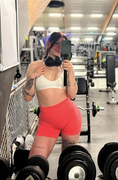 Ann Helen Lund tar et bilde og er kledd i en sexy hvit crop top og oransje tights.