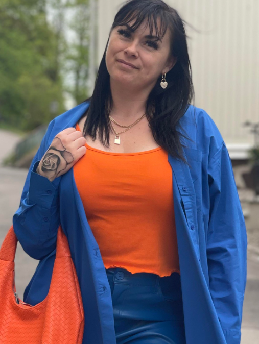 Lene Antonsen iført jeansjakke og oransje t-skjorte inni, og bærer også en oransje veske