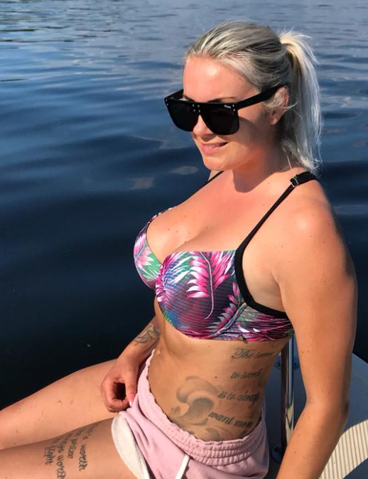 Lene Antonsen har på seg en parasoll og tar et bilde foran et basseng