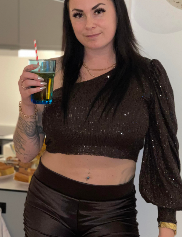 Lene Antonsen drikker av en vinkopp i brun topp